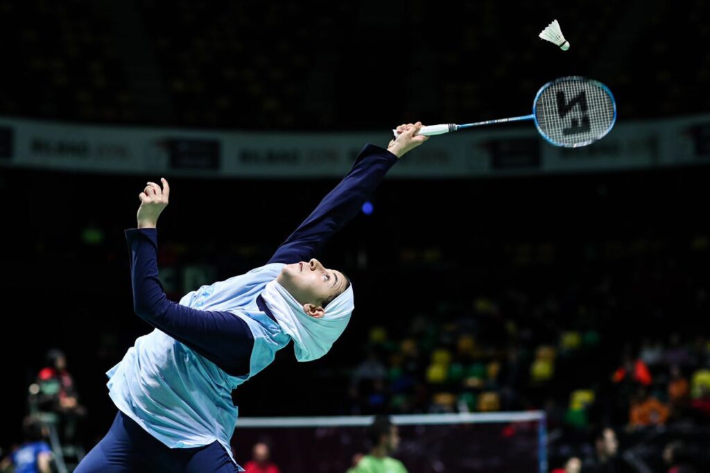 Samin Abedkhojasteh reaching for shuttlecock on badminton court