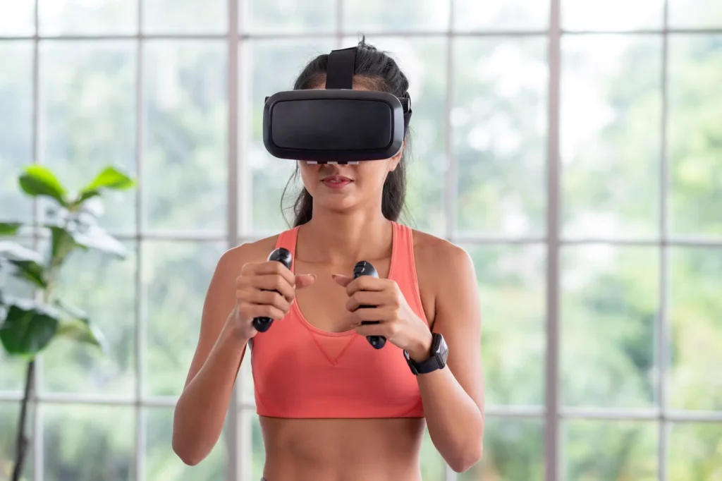 A young woman with a VR headset and hand gadgets on practicing boxing