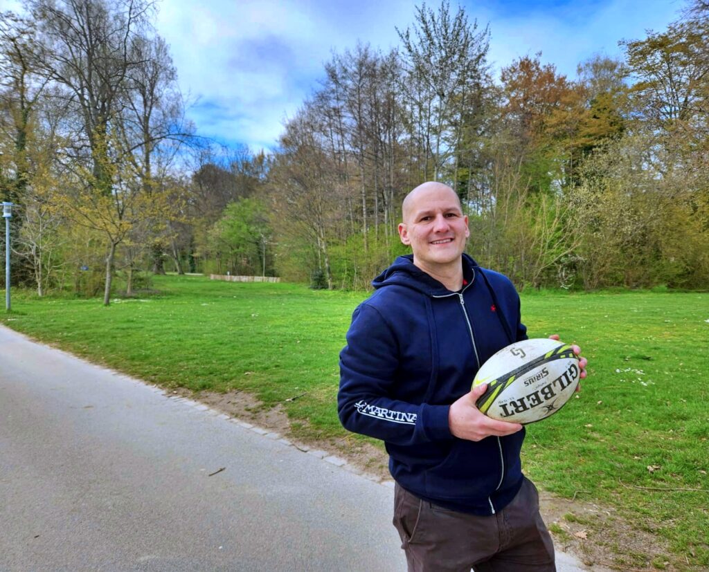 Daniel Golding holding a rugby ball in a park