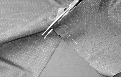 Scissors cutting technical fabric along a seam during textile testing process