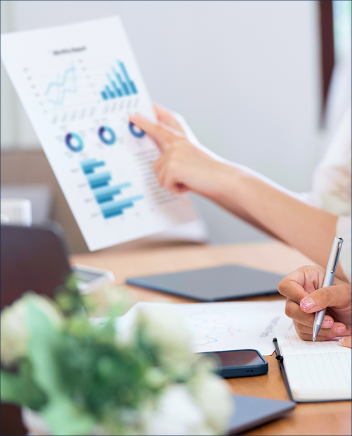 Close-up of hands reviewing charts and graphs during a sport event impact analysis session