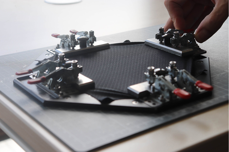 Hand adjusting a mechanical testing rig clamped onto a carbon-fiber sport equipment surface