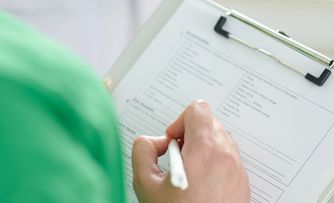 Hand filling out a Standards Compliance Checklist. AISTS offers Standards Compliance and Homologation for sport equipment