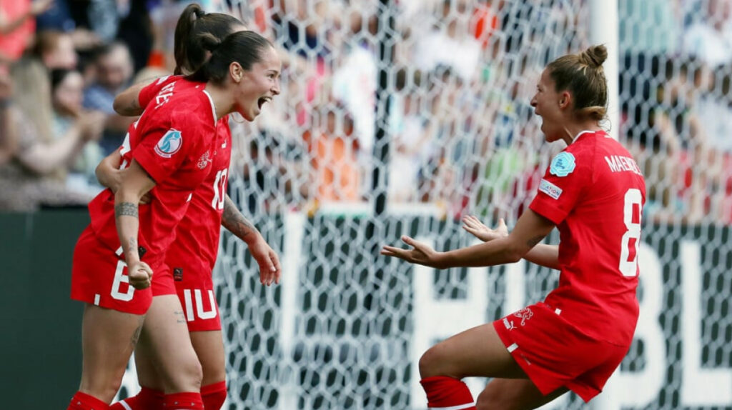 Swiss women's national football team players celebrating a goal during UEFA Women's EURO 2025 with excitement and passion near the goalpost.