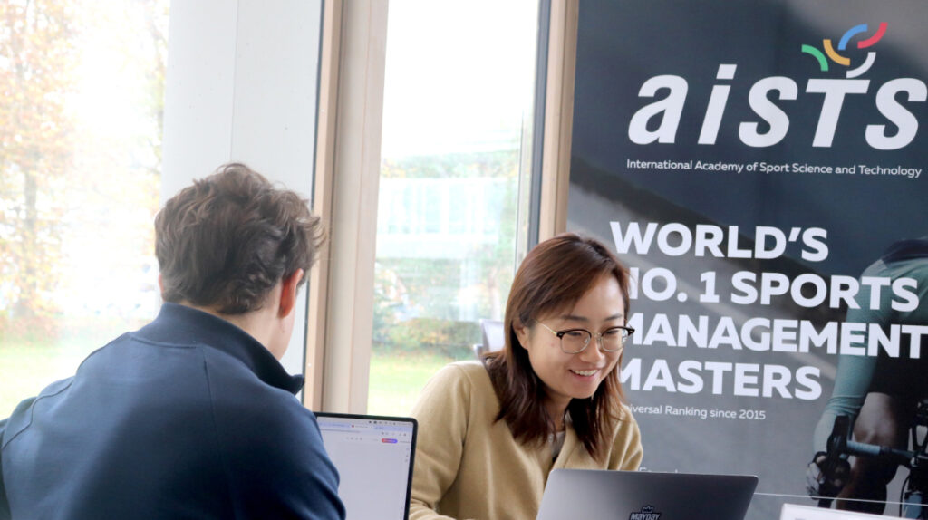 Students collaborating with laptops at AISTS representing education behind sports management in Europe.