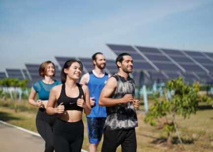Athletes running beside solar panels, illustrating sustainability in sport management.